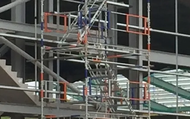 Multi-storey scaffolding stair tower erected against a steel-frame building