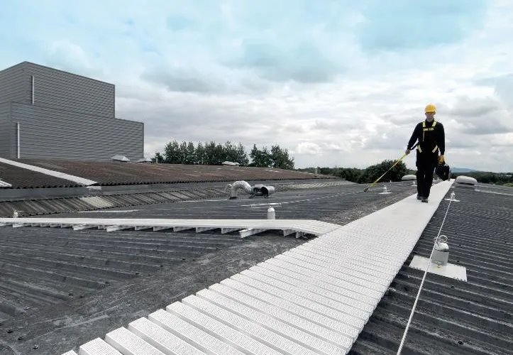 White anti-slip rooftop walkway with a worker clipped to an adjacent lifeline